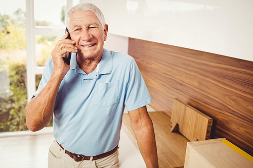 Smiling senior man on a phone call in living room
