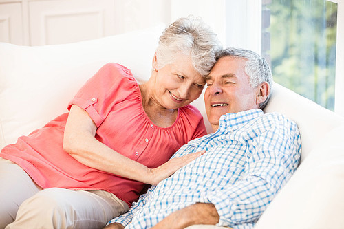 Happy senior couple lying on sofa at home