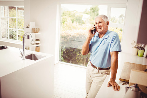 Smiling senior man on a phone call in the kitchen