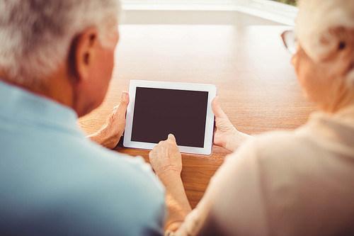 Rear view of senior couple using tablet at home