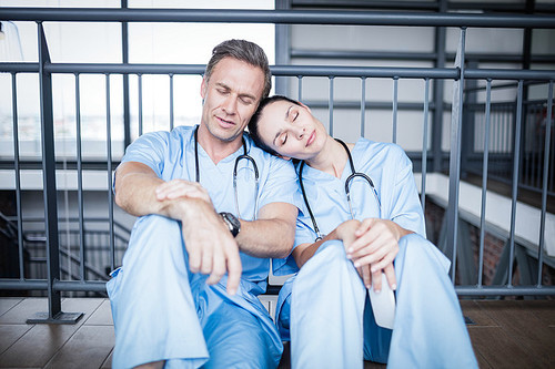 Tired medical team falling asleep on floor at hospital