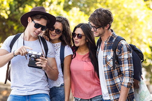 hip friends looking at digital camera outdoors