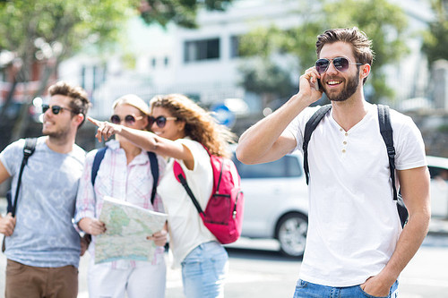 Hip man on phone call and friends checking map outdoors