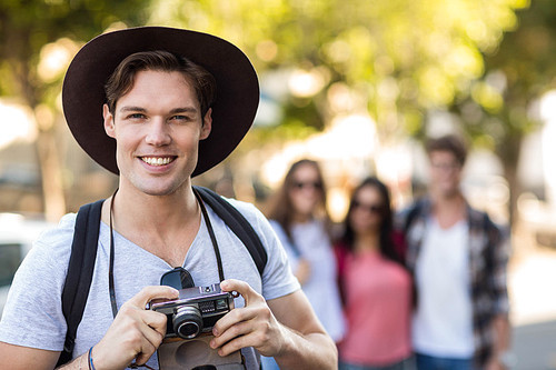 Hip man holding digital camera and smiling at the camera