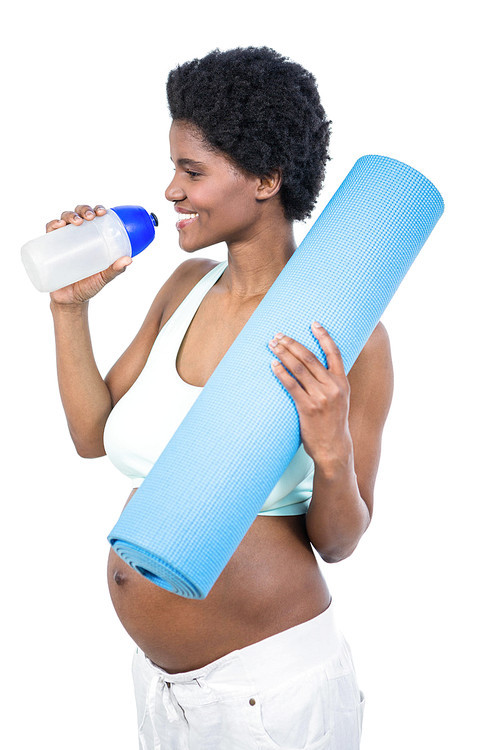 Pregnant woman holding water bottle and mat on white background