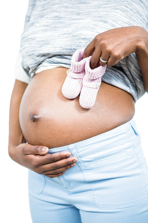 Pregnant woman holding baby shoe on white background