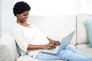 Pregnant woman using laptop on couch