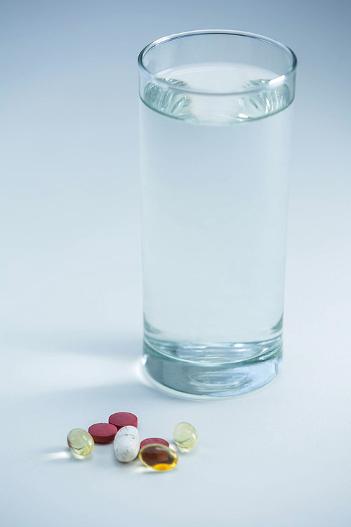 Pills beside glass of water on table