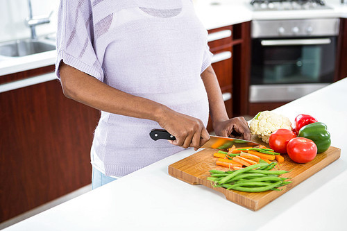 Pregnant woman preparing vegetables in kitchen