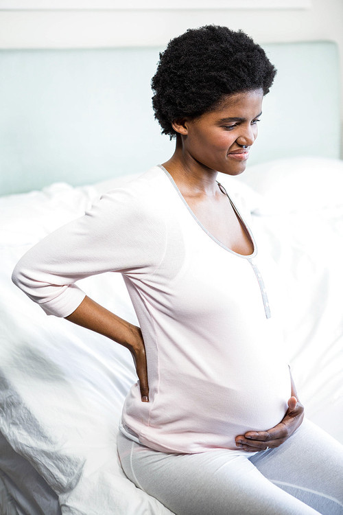 Pregnant woman with back pain in bedroom