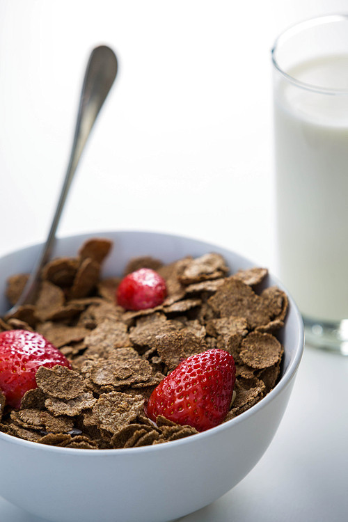 View of a bowl of cereals and glass of milk on a table