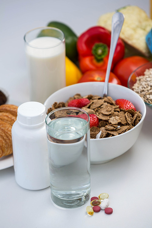 View of bowl of cereals, pills and food on a white table