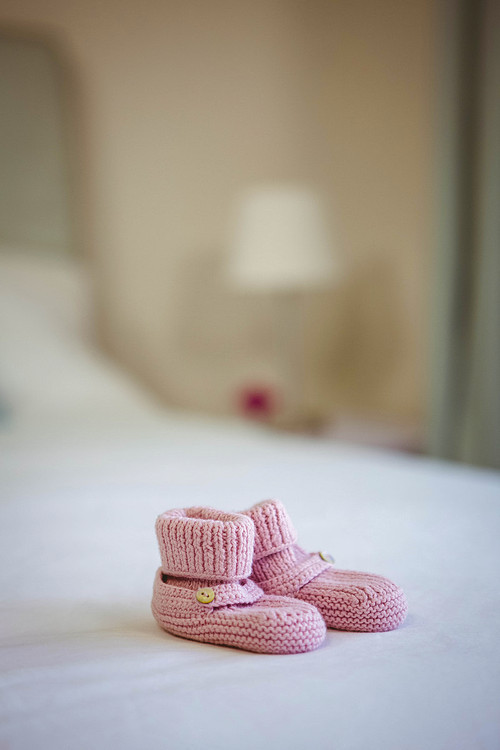 View of baby shoes on a bed at home