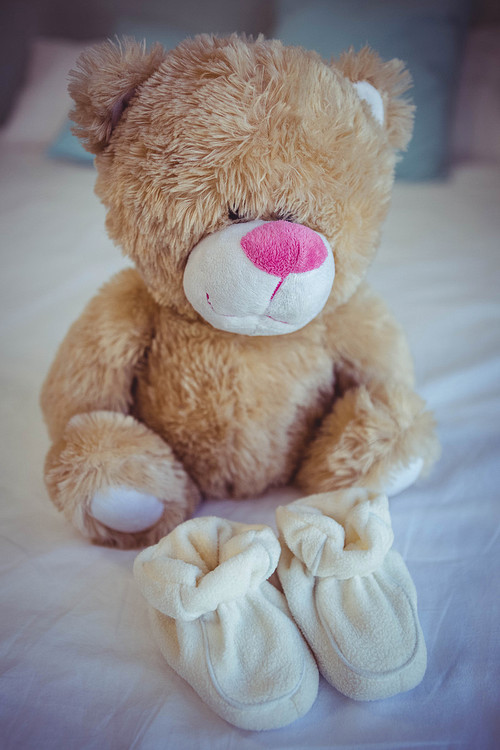 View of teddy bear and baby socks on a bed