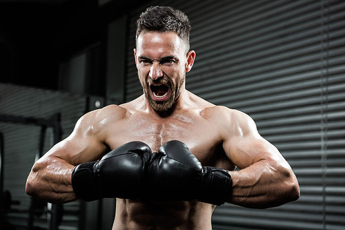Angry shirtless man with boxe gloves shouting at the crossfit gym