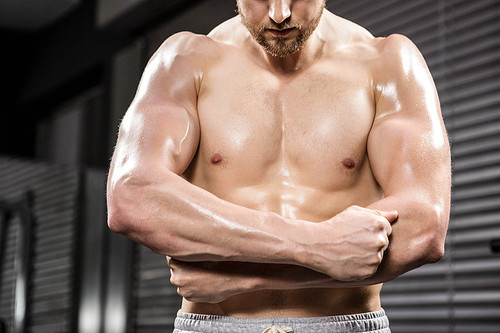 Shirtless man flexing biceps at the crossfit gym