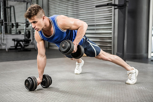 Muscular man doing push up with dumbbells at the crossfit gym