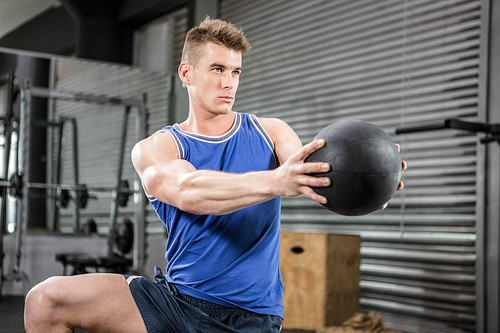 Muscular man training with medicine ball at the crossfit gym