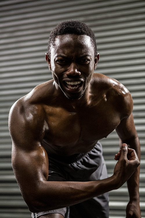 Shirtless man showing biceps at the crossfit gym