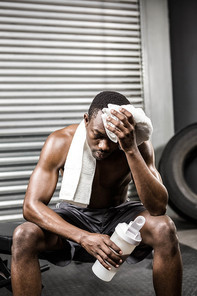 Shirtless man wiping sweat with towel at the crossfit gym