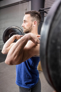 Muscular man lifting barbell at the crossfit gym