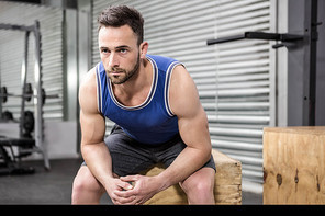 Muscular man sitting on wooden block at the crossfit gym