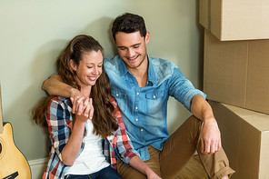 Young couple sitting together on the floor and smiling in their new house