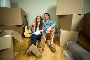 Young couple sitting together on the floor and smiling in their new house