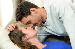 Young couple about to kiss on sofa in living room