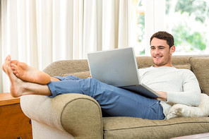 Young man using laptop on sofa in living room