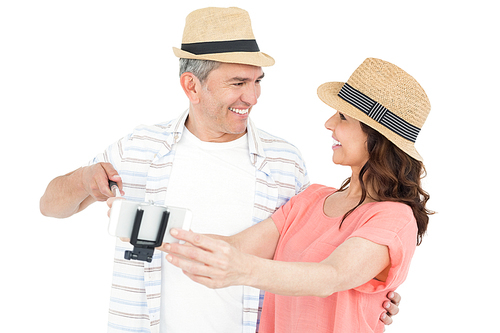 Happy couple using a selfie stick on white background
