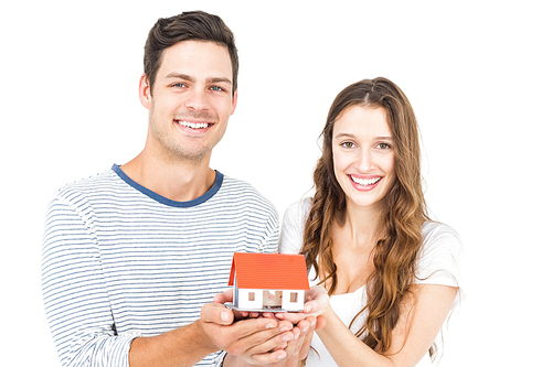 Happy couple holding miniature house on white background