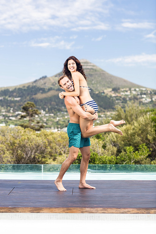 Portrait of young couple enjoying near pool on a sunny day