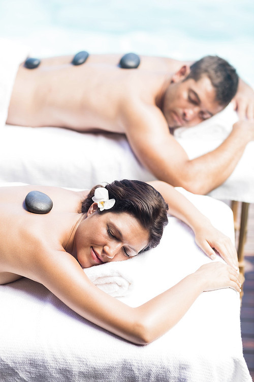 Couple getting a hot stone massage by the pool