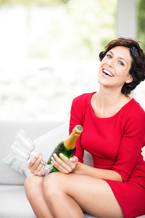 Portrait of beautiful woman smiling and holding champagne bottle and glass