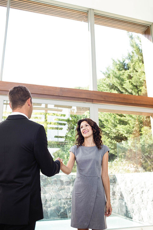 Young woman ready to buy new house shaking hands with estate-agent