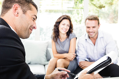 Young couple ready to buy new house interacting with estate-agent