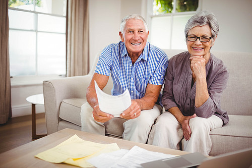 Portrait of senior couple sitting on sofa and smiling in living room