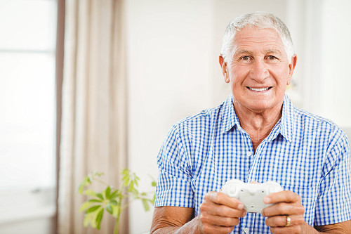 Senior man with joystick  and smiling in living room
