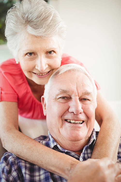 Portrait of senior woman embracing man in living room