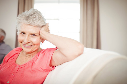 Happy senior woman sitting on sofa in living room