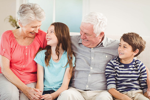 Grandparents and grandchildren sitting together on sofa in living room