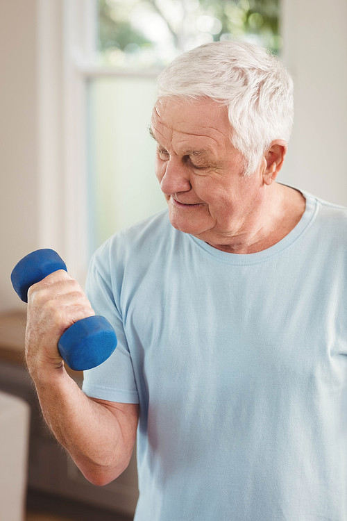 Senior man exercising with dumbbells at home