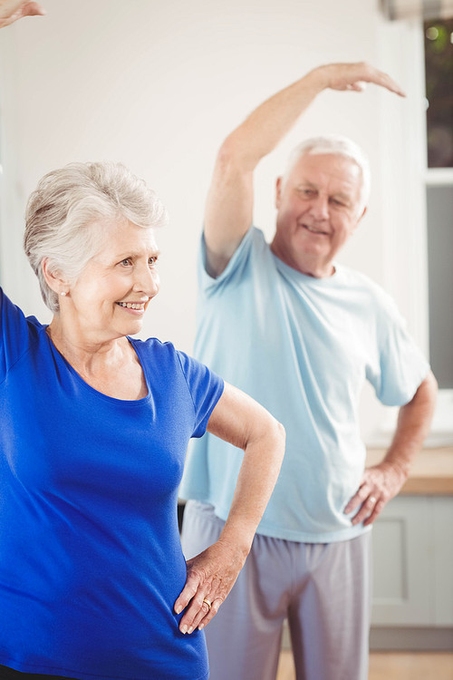 Senior couple performing stretching exercise at home