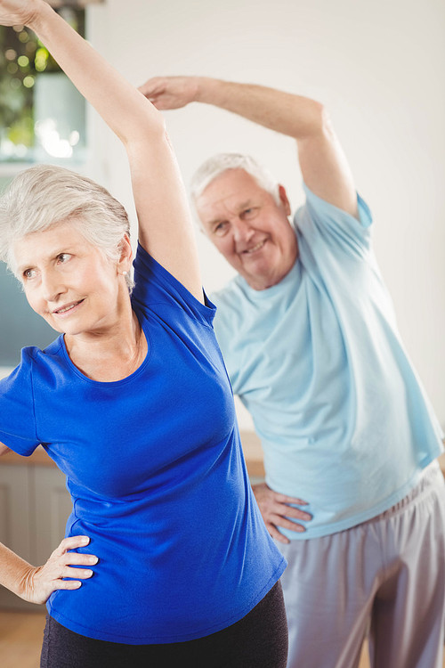 Senior couple performing stretching exercise at home