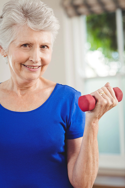 Portrait of senior woman exercising with dumbbells at home