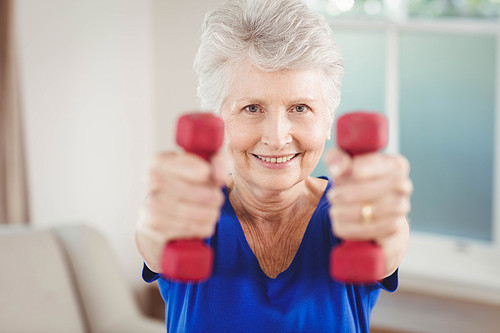 Portrait of senior woman exercising with dumbbells at home