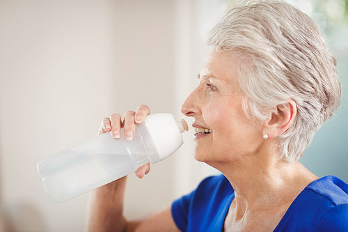 Happy senior woman drinking water after a workout