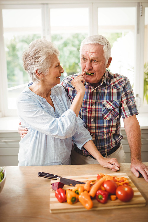 Senior woman feeding a cucumber slice to senior man