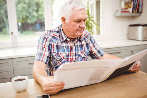 Senior man reading a newspaper at home
